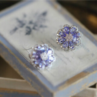 A pair of 925 silver stud earrings inlaid with multiple tanzanites, set against a sea of dazzling flowers and galaxies. a pair of stud earrings.